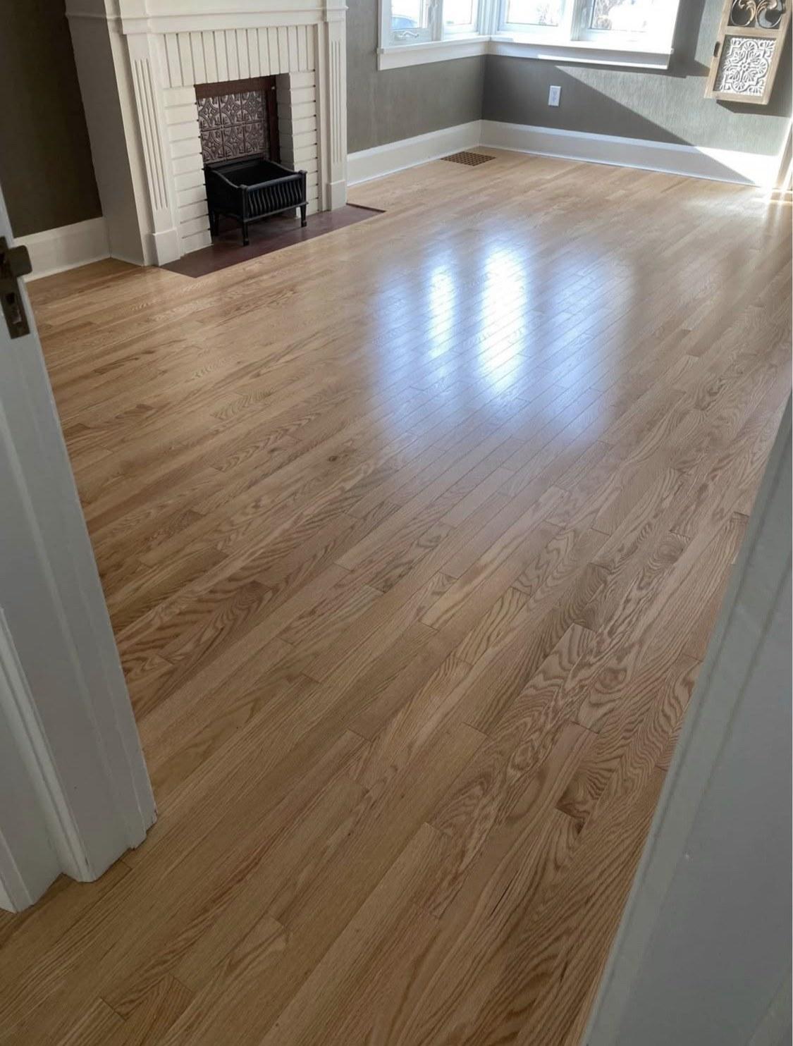 Bright living room with a finished light natural wood floor and white fireplace